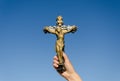 Metal cross crucified christ in hand on blue sky