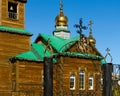 Metal cross on the fence at the entrance to the Orthodox Church with domes and crucifixes.