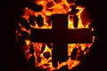 The metal cross lies on the burning coal of a small fraction.