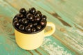 Metal cup with blackcurrant on the blue and white wooden background. Royalty Free Stock Photo