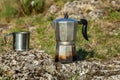 Metal cup and coffee maker in nature. Making coffee. Camping in summer