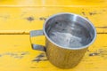 A metal cup of fresh water on yellow table