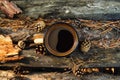 Metal cup with hot coffee on the wooden background with the coins, needles and bark of tree, top view.