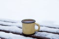 Metal cup with hot tea on a snow-covered bench in a winter park Royalty Free Stock Photo