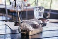 Metal cutlery forks spoons knives in black stones candlestick. Water glass cube, wineglass wooden table on napkin