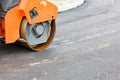 The wheel of a large road vibratory roller compacts fresh asphalt of the new road