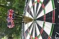 Metal darts have hit the red bullseye on a dart board. Darts Game. Darts arrow in the target center darts in bull`s eye close up. Royalty Free Stock Photo
