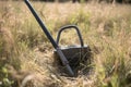 a metal detector, with a rope attached to the handle and being dragged through the tall grass