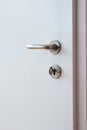 Metal door lock handle and key on wooden white interior door isolated close up shot Royalty Free Stock Photo