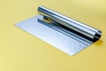 Metal dough scraper knife over bright yellow surface background. Stainless steel flat dough scraper Royalty Free Stock Photo