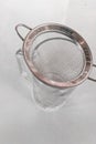 Metal drink strainer on glass cup on white table