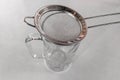 Metal drink strainer on glass cup on white table