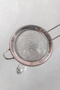 Metal drink strainer on glass cup on white table