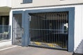 Metal driveway private entrance residence property building door gate set in brick fence with car park in background