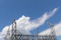 Metal electric power truss structures silhouetted against a brilliant blue sky with dramatic white clouds, creative copy space
