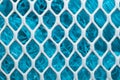 Metal enameled grid. abstract background. blue cloth behind the metallic grate Royalty Free Stock Photo