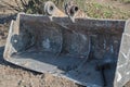 Metal excavator bucket with stiffening ribs inside and eyelets on top, at the bottom of bucket on right is sledgehammer.