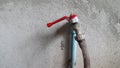 Metal faucet red handle with house  on gray cement concrete wall. Royalty Free Stock Photo