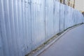 A metal fence along the sidewalk. Fences of the construction site. Royalty Free Stock Photo