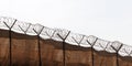 Metal fence with barbed wire on sky background.