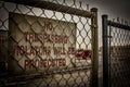 Metal fence with a sign reading "No Trespassing" in bold red lettering.