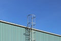 Metal fire escape on the roof of an industrial building against the blue sky. Safety of the work of people. Evacuation during stoi Royalty Free Stock Photo