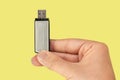 Metal flash drive on hand with isolated yellow background