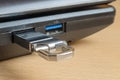 A metal flash drive in the usb slot of a laptop close-up.