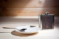 A metal flask and a saucer with a teaspoon on a wooden surface Royalty Free Stock Photo