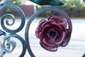 Metal flower in the design of a forged gate close-up, an iron flower dark red, craft element of decor