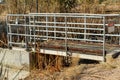 Metal footbridge in industrial area to cross over to hand wheele valve to turn on and off the flow of water in sun