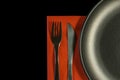 Metal fork, knife on red napkin and plate on a black background. top view on stainless knife and fork with copy space