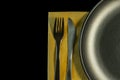 Metal fork, knife on yellow napkin and plate on a black background. top view on stainless knife and fork with copy space