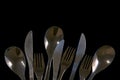 Metal forks, knives and spoons on a black background. top view on stainless knives, spoons and forks with copy space