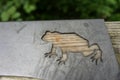 Metal frog sculpture on wood rail