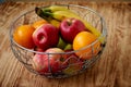 Metal fruit bowl on a wooden surface. Close. Bananas, oranges and apples Royalty Free Stock Photo