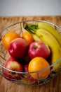 Metal fruit bowl on a wooden surface. Close. Bananas, oranges and apples Royalty Free Stock Photo