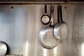 Metal frying pans hanging on a rack in an industrial restaurant kitchen