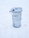 Metal garbage can with lid closed on the snow Royalty Free Stock Photo