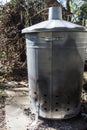 Metal garden incinerator bin in a garden yard.