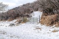 Metal gate on a mountain pathway covered with snow on a cloudy winter day Royalty Free Stock Photo