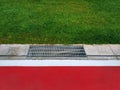 Metal Grating By Red Floor and Green Grass Field Royalty Free Stock Photo
