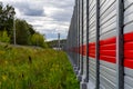 Metal gray fence with red stripe, thick pre-rain clouds and summer colorful landscape Royalty Free Stock Photo