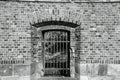 Metal grid in arched entrance of brick wall.Black and white photo. Royalty Free Stock Photo