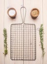 Metal grid for cooking with rosemary and spices on white rustic background, place for text Royalty Free Stock Photo