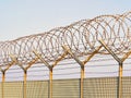 Metal grid fence with loops of Concertina razor wire and barbed wire