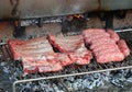 metal grill of alfresco barbecue and sausages and pork ribs are cooking with wood fire