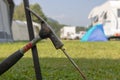 Metal hammer putting a nail-like tent peg out of iron into the grass.