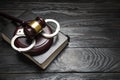 Metal handcuffs, book and judge gavel on the table