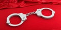 Metal handcuffs on red satin background, 3d illustration